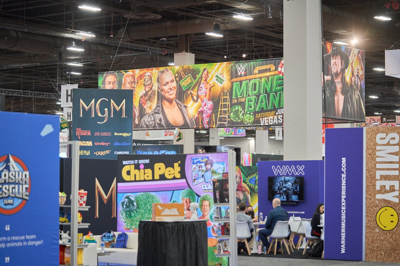 A group of different exhibitor stands on the Licensing Expo showfloor including WWE, Smiley, MGM, and Chia Pet.
