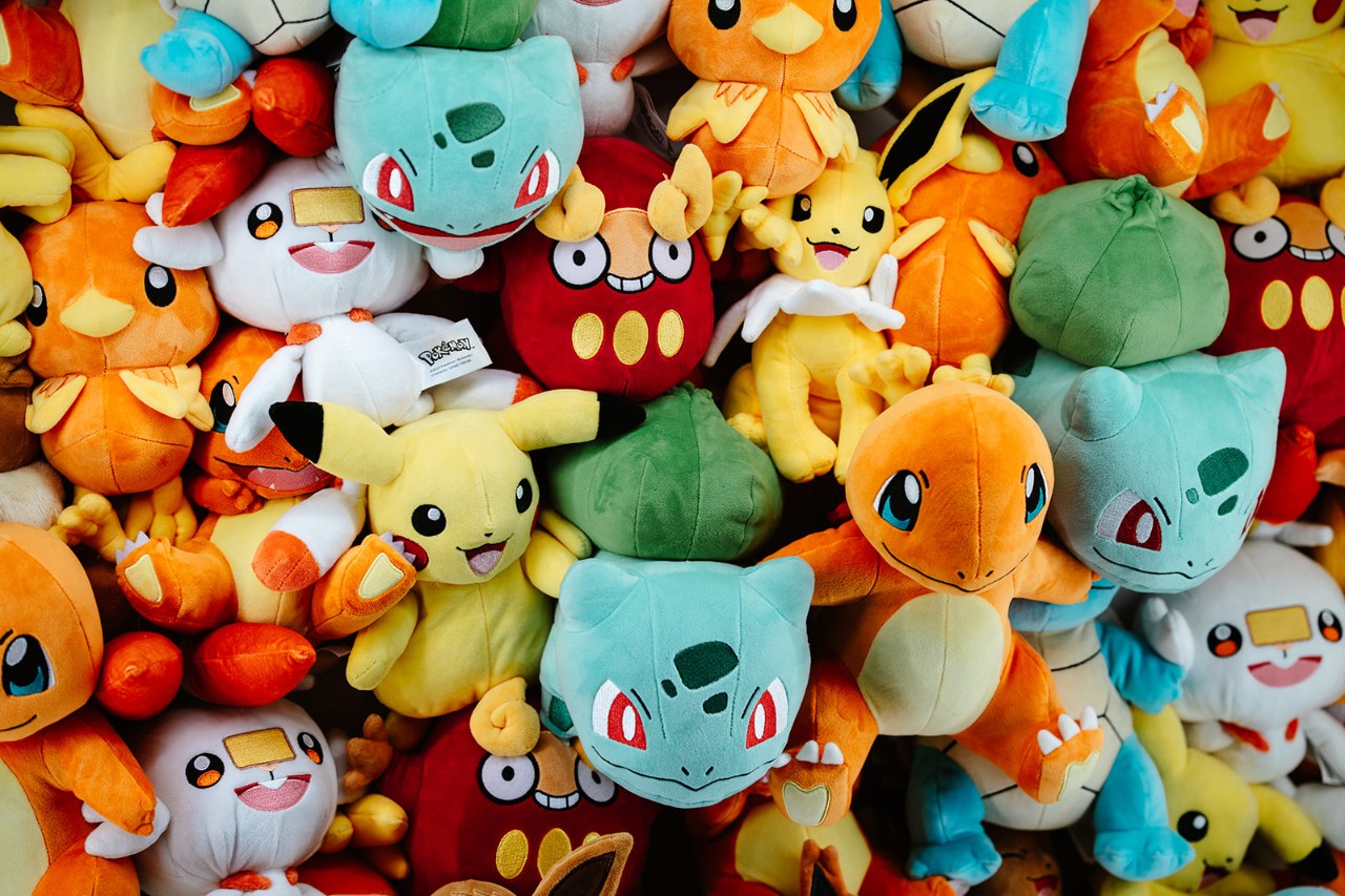 ile of Pokémon plush toys featuring popular characters including Pikachu, Bulbasaur, Charmander, Torchic, and Darumaka. Officially licensed Pokémon merchandise showcased at a retail or event display